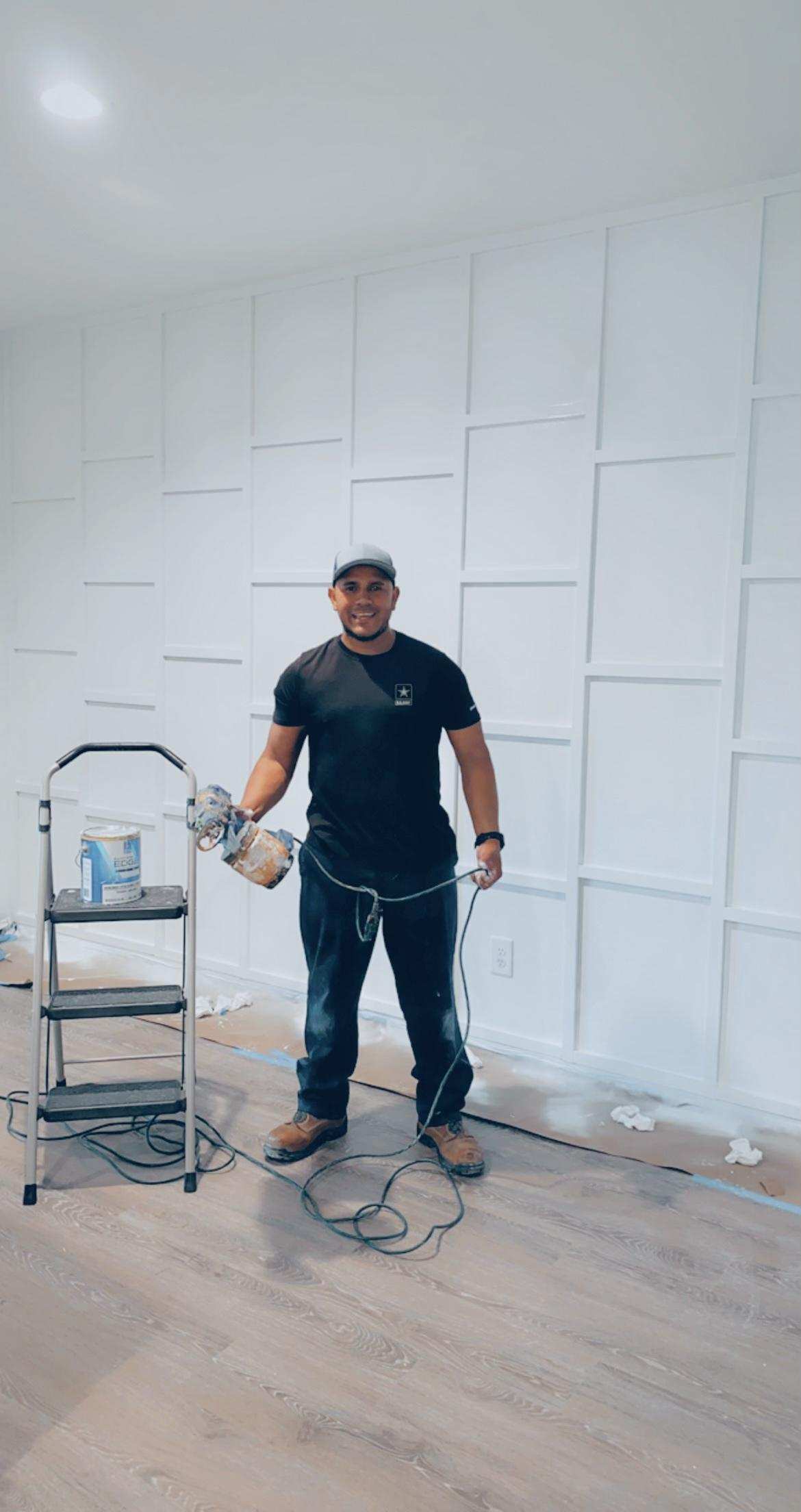 HL Construction founder holding a paint sprayer beside a finished paneled wall